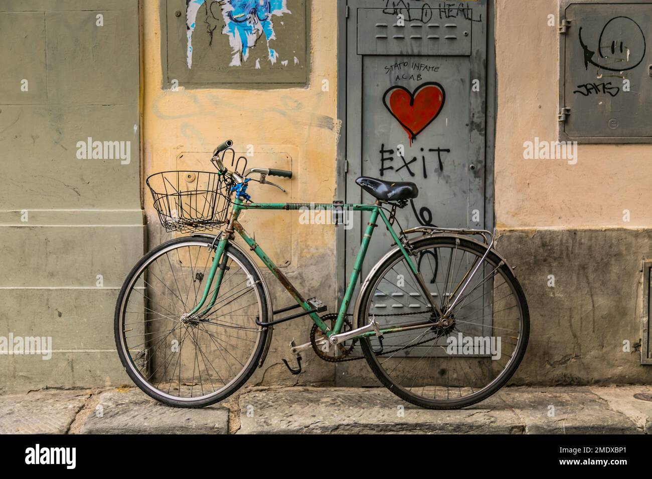 Green bicycle parked in front of street art on door in Florence, Tuscany, Italy. Stock Photo