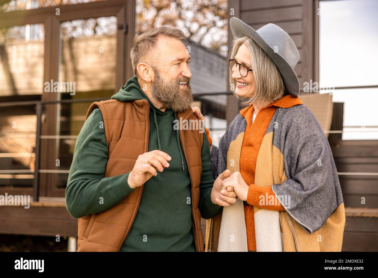 Happy man and woman standing near their new house and smiling Stock Photo