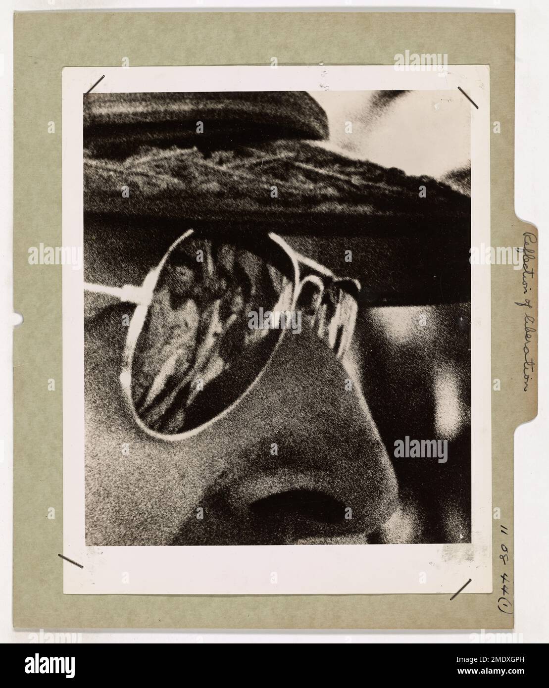 Photograph of Reflection in General MacArthur's Glasses. Reflection of Liberation. Reflected in General MacArthur's glasses are figures of the Filipino natives greeting his return joyously on the beach of Leyte Island after the island had been under Jap oppression for nearly three years. This enlargement of a closeup photo of MacArthur was made by a Coast Guard Combat Photographer who held his camera on the general for ten minutes waiting for the exact instant to snap this remarkable picture. General MacArthur was standing on Leyte's beach soon after landing to keep his famous 'I Shall Return' Stock Photo