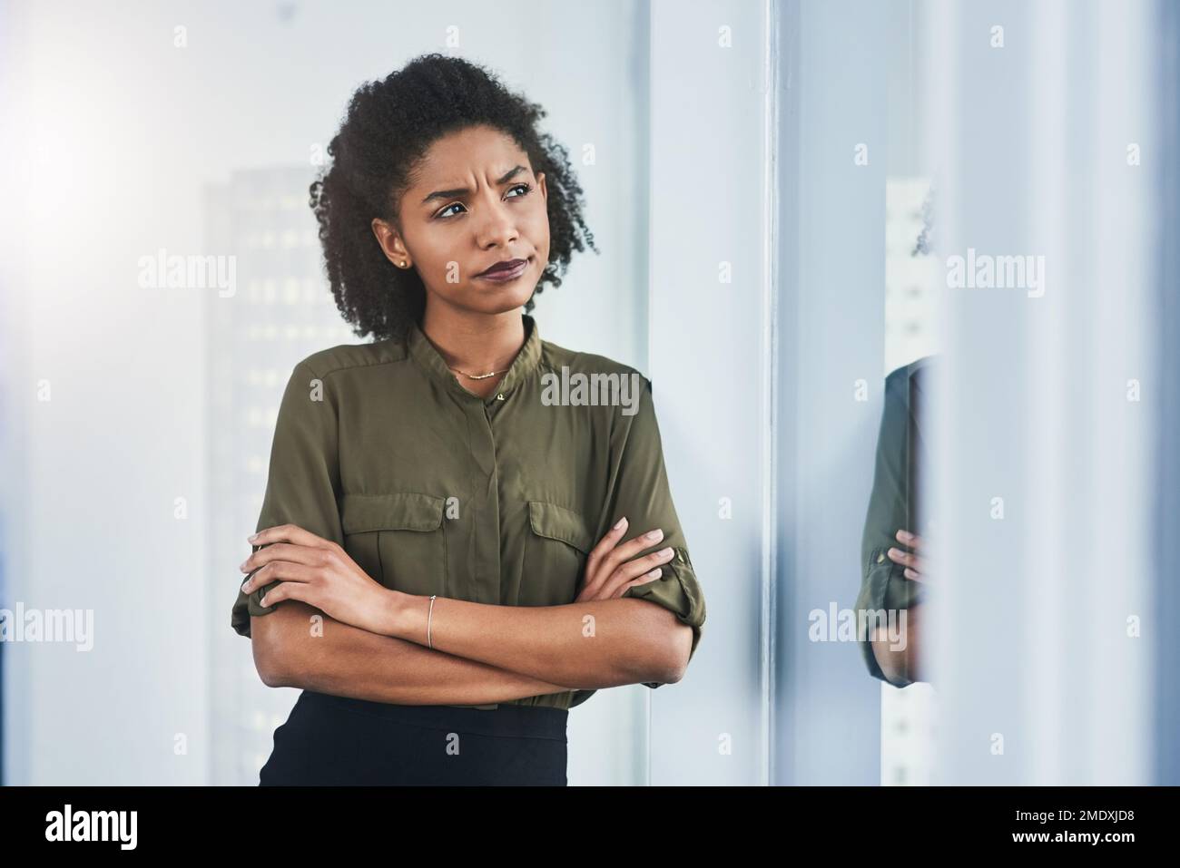 Ideas only turn into reality when you pursue them. a young businesswoman looking out of a window in her office. Stock Photo