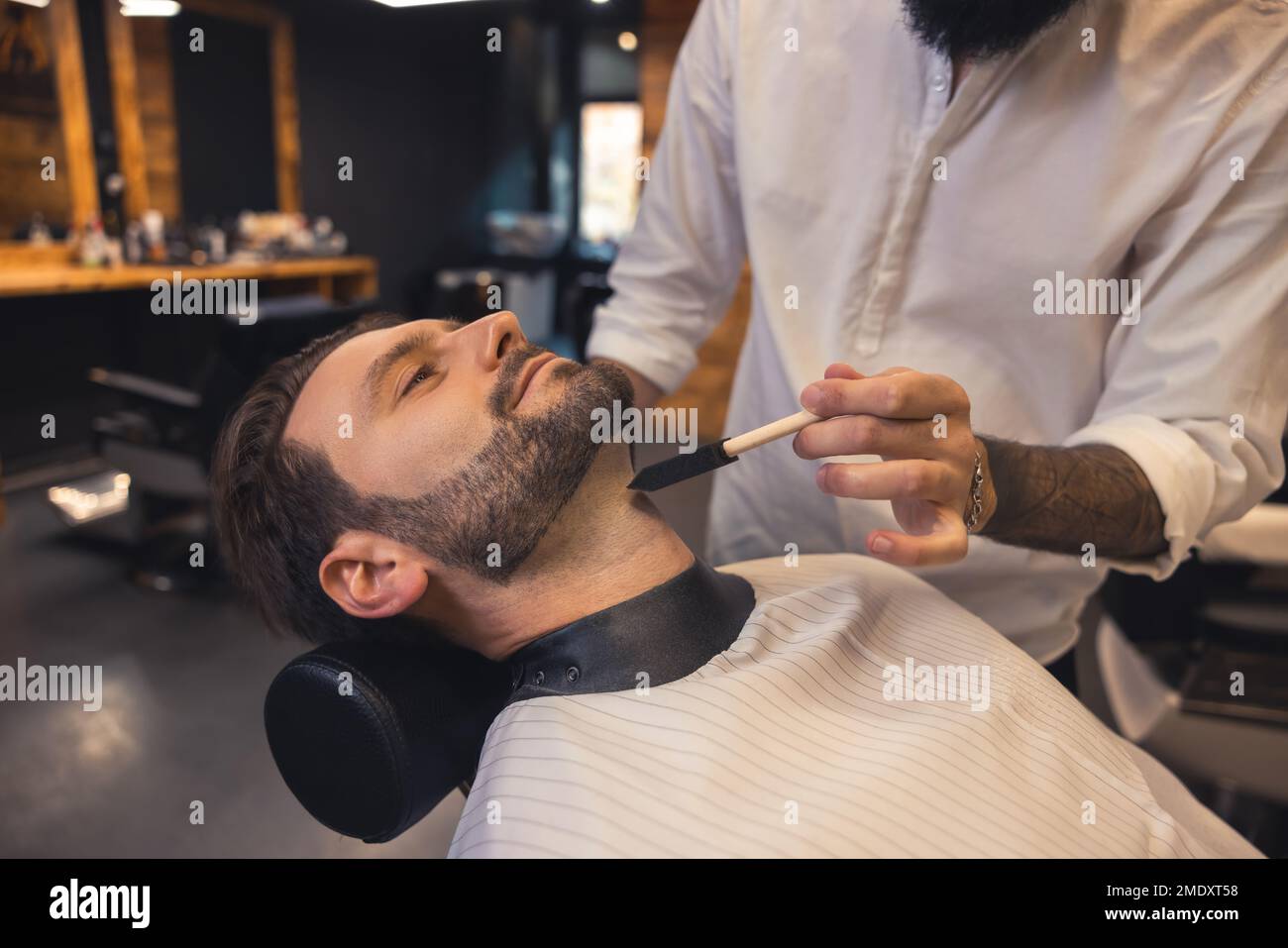 Barber in the salon working on the clients beard Stock Photo