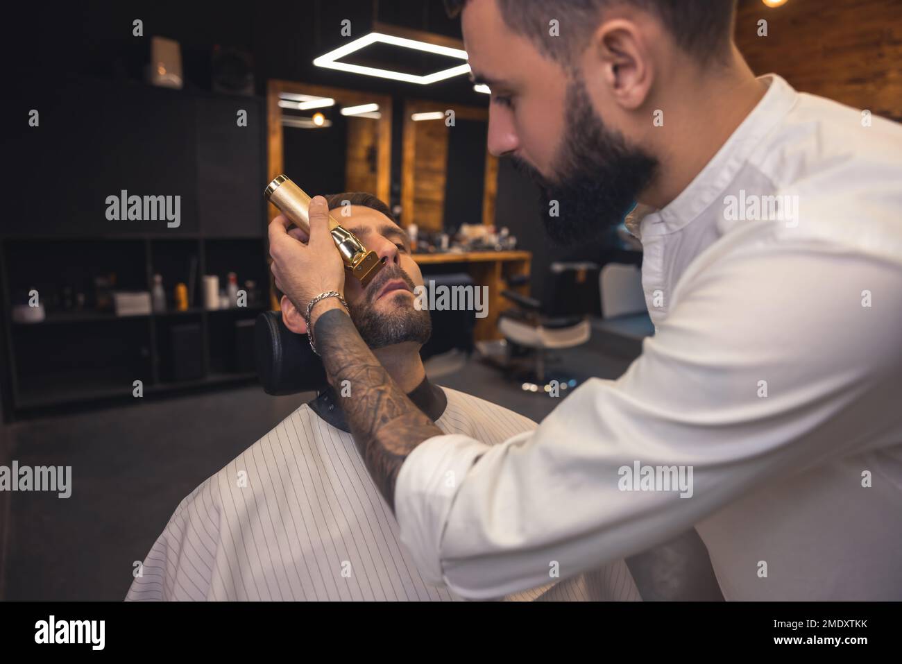 Barber in the salon working on the clients beard Stock Photo