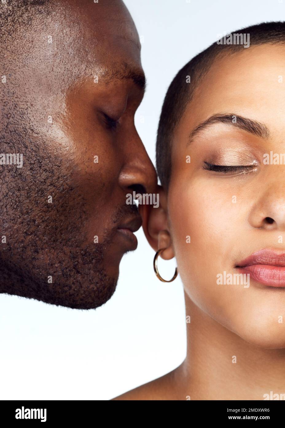 The scent of love lingers all around us. Studio shot of a couple posing with their eyes closed against a grey background. Stock Photo