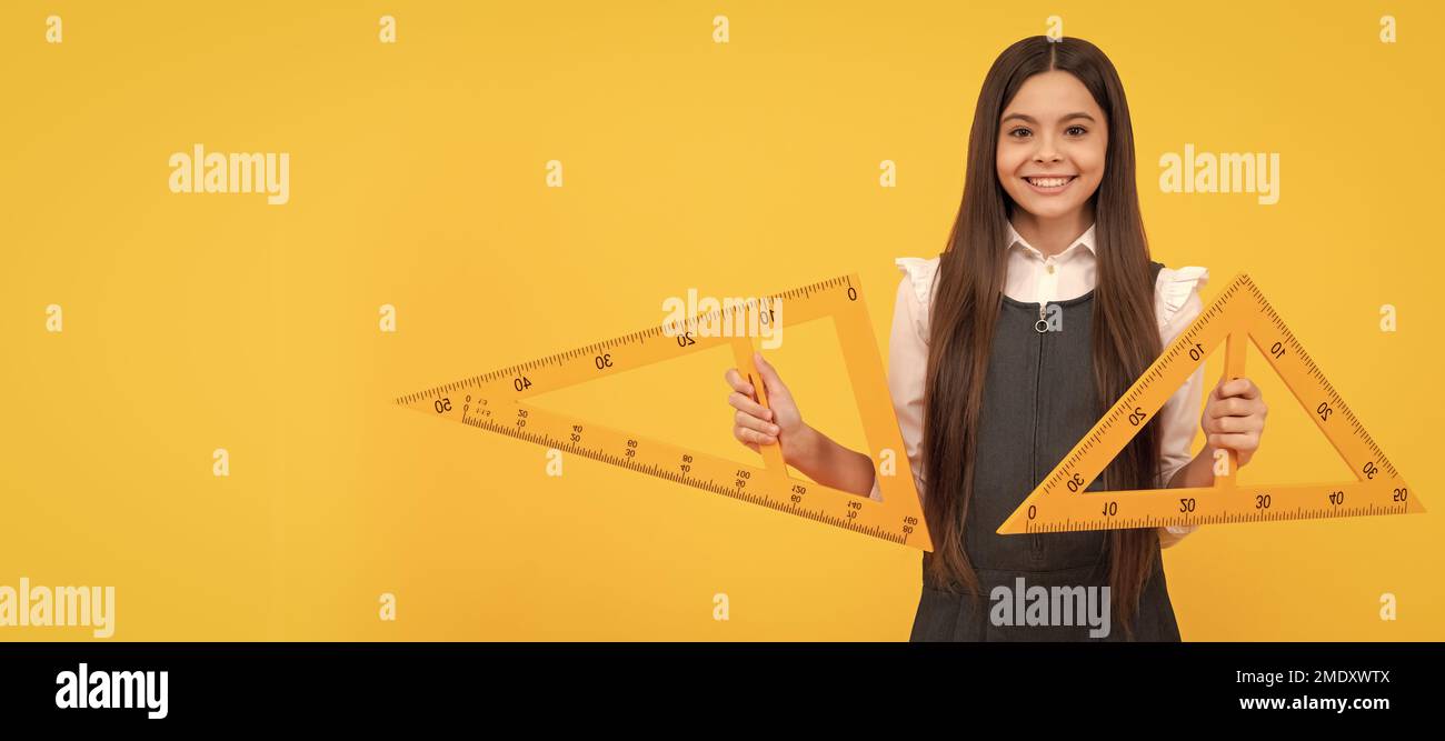 cheerful teen girl hold math triangle ruler in school on yellow ...