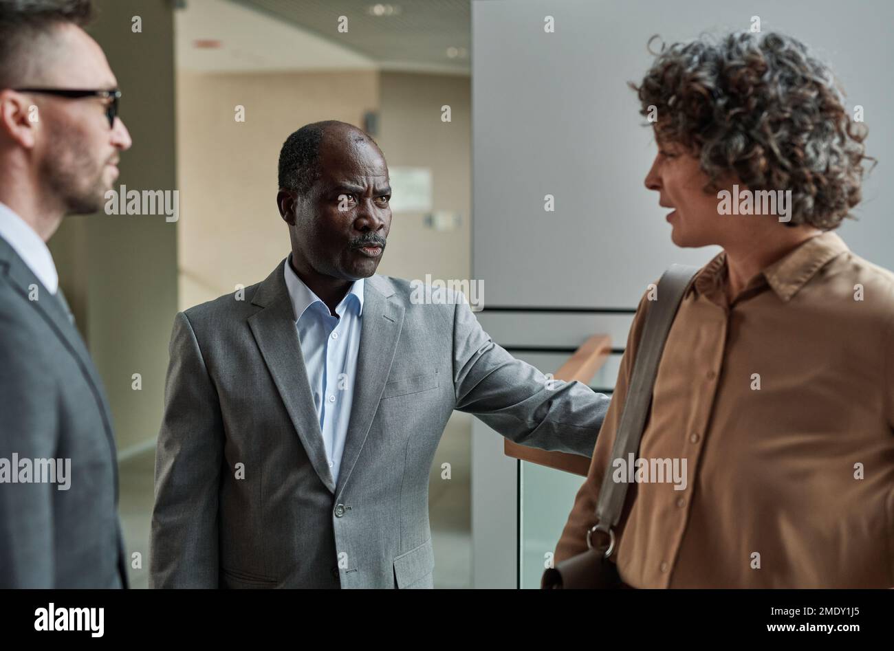 Strict mature boss dissatisfied with female subordinate scolding her at meeting while explaining reason for his discontentment Stock Photo