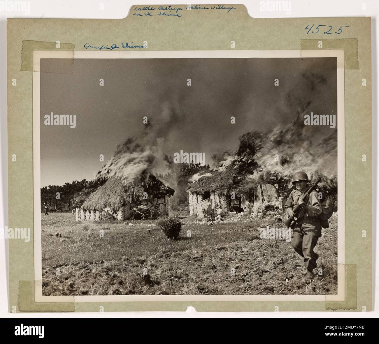 Battle Destroys Native Village on Ie Shima. Thatched-roof huts of the natives go up in flame as American invaders drive back the Japs who opposed their landings on Ie Shima. Here, a Coast Guard combat photographer catches veterans of the Army's 77th division moving up through a burning village. Ie Shima is in the Ryukyu chain close to Okinawa. Stock Photo