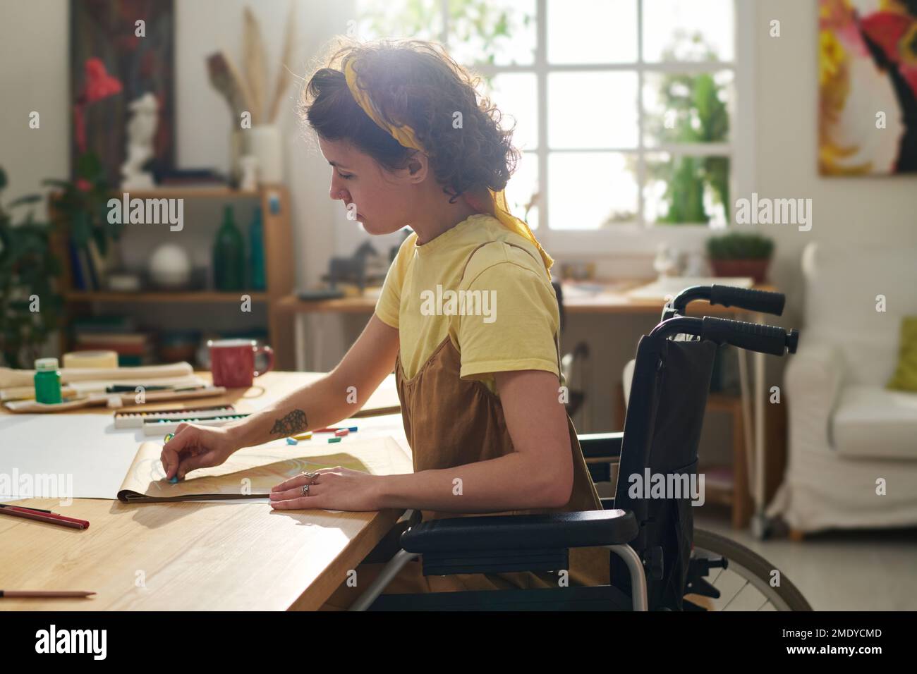 Young inspired woman with disability in wheelchair creating new artwork
