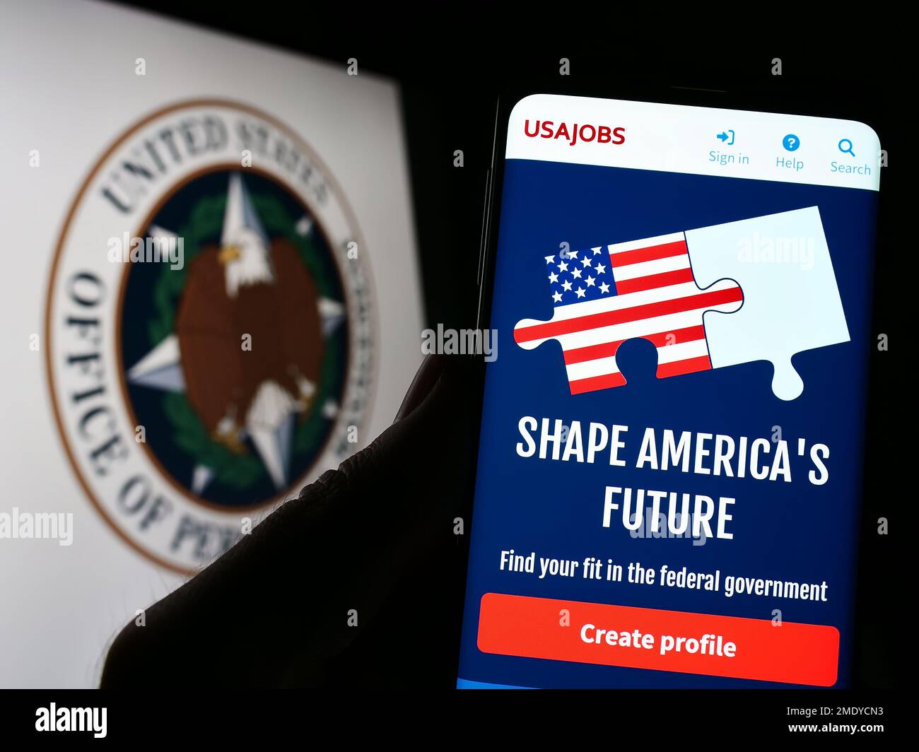Person holding cellphone with webpage of us office of personnel