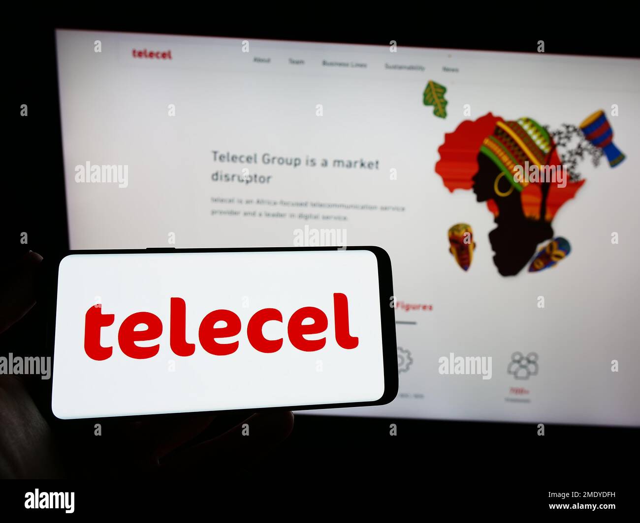 Person holding smartphone with logo of telecommunications company Telecel Group on screen in front of website. Focus on phone display. Stock Photo