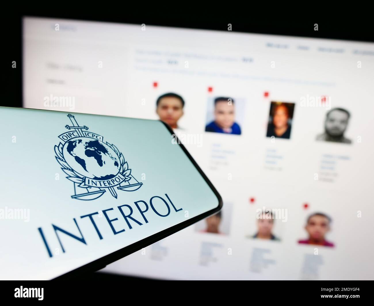 Mobile phone with logo of International Criminal Police Organization (ICPO) on screen in front of website. Focus on phone display. Stock Photo