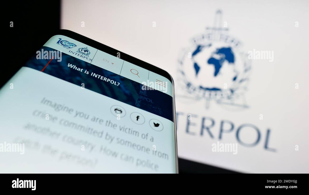 Smartphone with website of International Criminal Police Organization (ICPO) on screen in front of logo. Focus on top-left of phone display. Stock Photo
