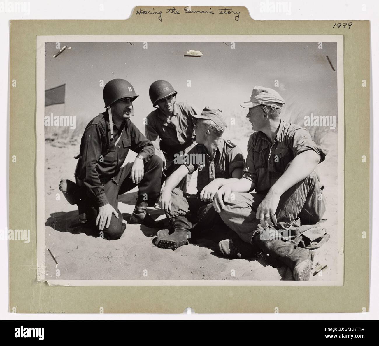 Hearing the Germans' Story. Two captured members of the German panzer division that made it hot for the Americans at Salerno tell an American army officer and a Coast Guardsman what the battle looked like from the German side. The Americans are Captain James H. Whitman, left, of White Plains, New York, and Coast Guardsman Philip E. Mannheimer, second from left, of Cliffside, New Jersey. Coast Guardsmen participated with the Navy in manning combat transports and landing craft. Stock Photo