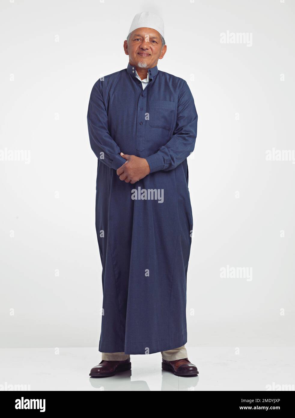 Muslim old man, studio portrait and islamic culture standing isolated on white background with arabic clothes. Senior moslem person, eid mubarak and Stock Photo