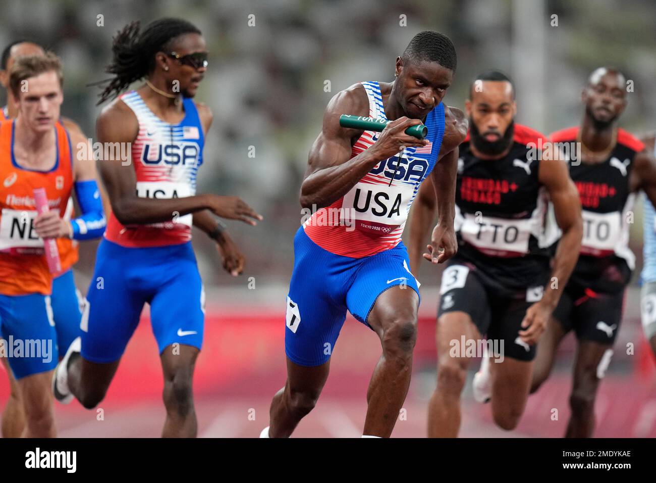 Runners from the United States exchange their baton during a heat of ...