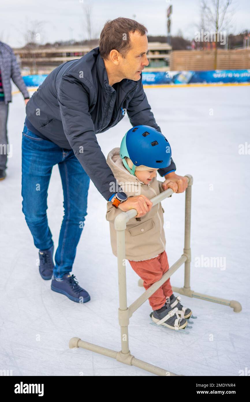 Prague, Czech republic - January 1, 2023: Father and little daughter learning to skate in winter in one of Prague ace rink Stock Photo