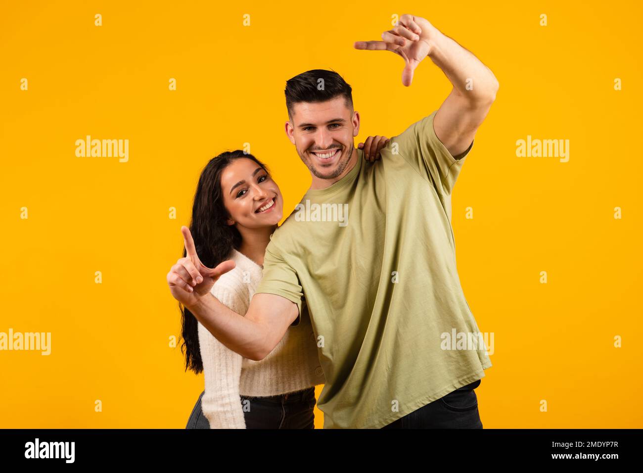 Happy millennial arabic husband and wife make hands lens, look through foreshortening Stock Photo