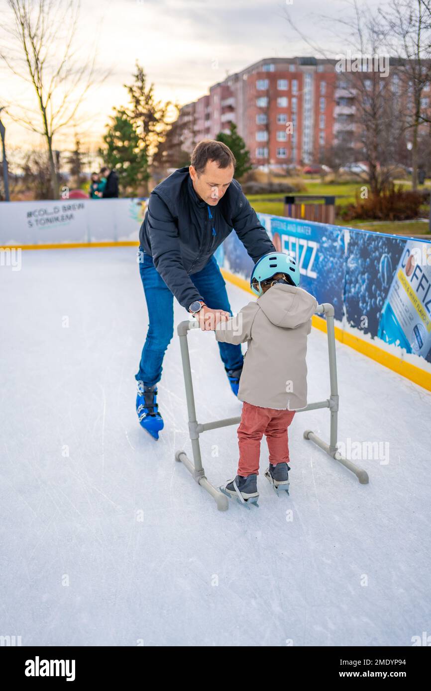 Prague, Czech republic - January 1, 2023: Father and little daughter learning to skate in winter in one of Prague ace rink Stock Photo