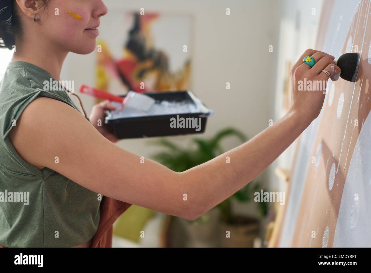 Close-up of young creative woman making white paint prints on panel where creating new abstract artwork in home studio or workshop Stock Photo