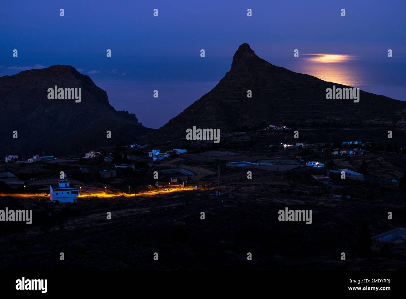 View over the village of Ifonche to the coastal resorts of Los Cristianos and Las Americas at dawn with the full moon setting in the west, Adeje, Tene Stock Photo