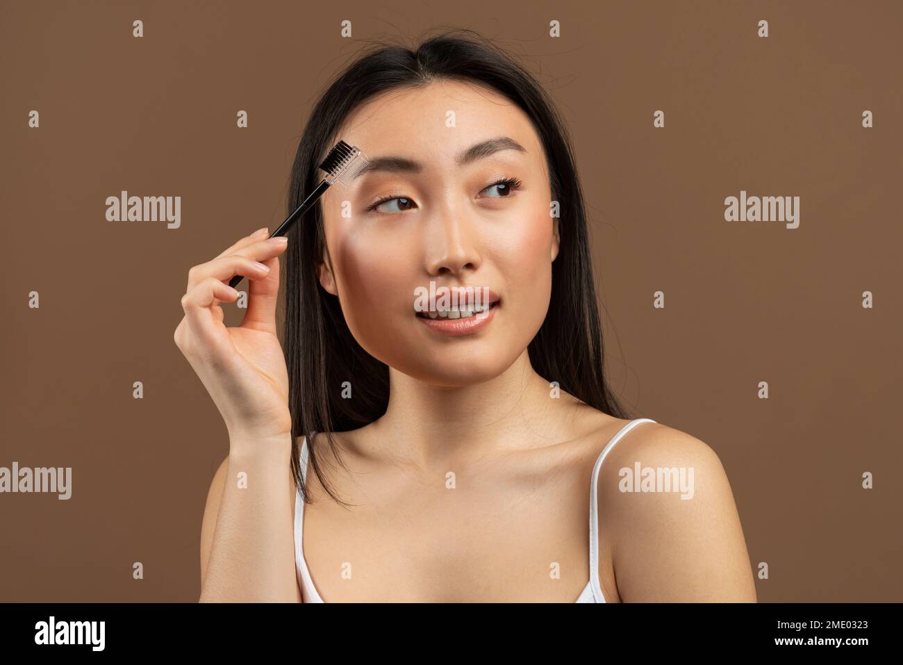 Beautiful young japanese lady brushing brows and applying eyebrow