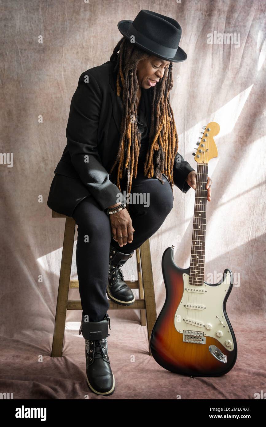 Senior African American Woman Picking Up Electric Guitar Stock Photo