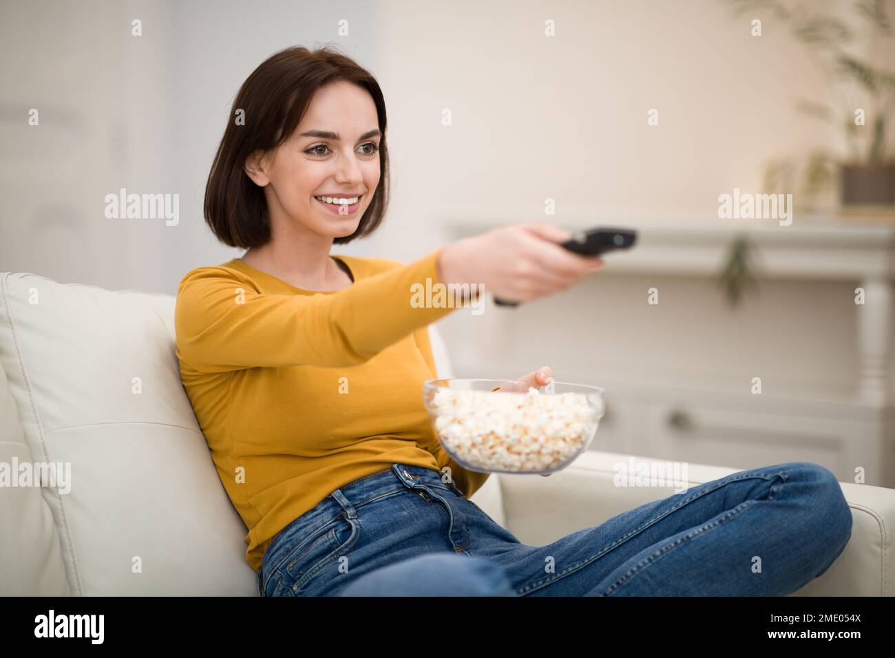 Young woman watching TV, movies with popcorn at home Stock Photo