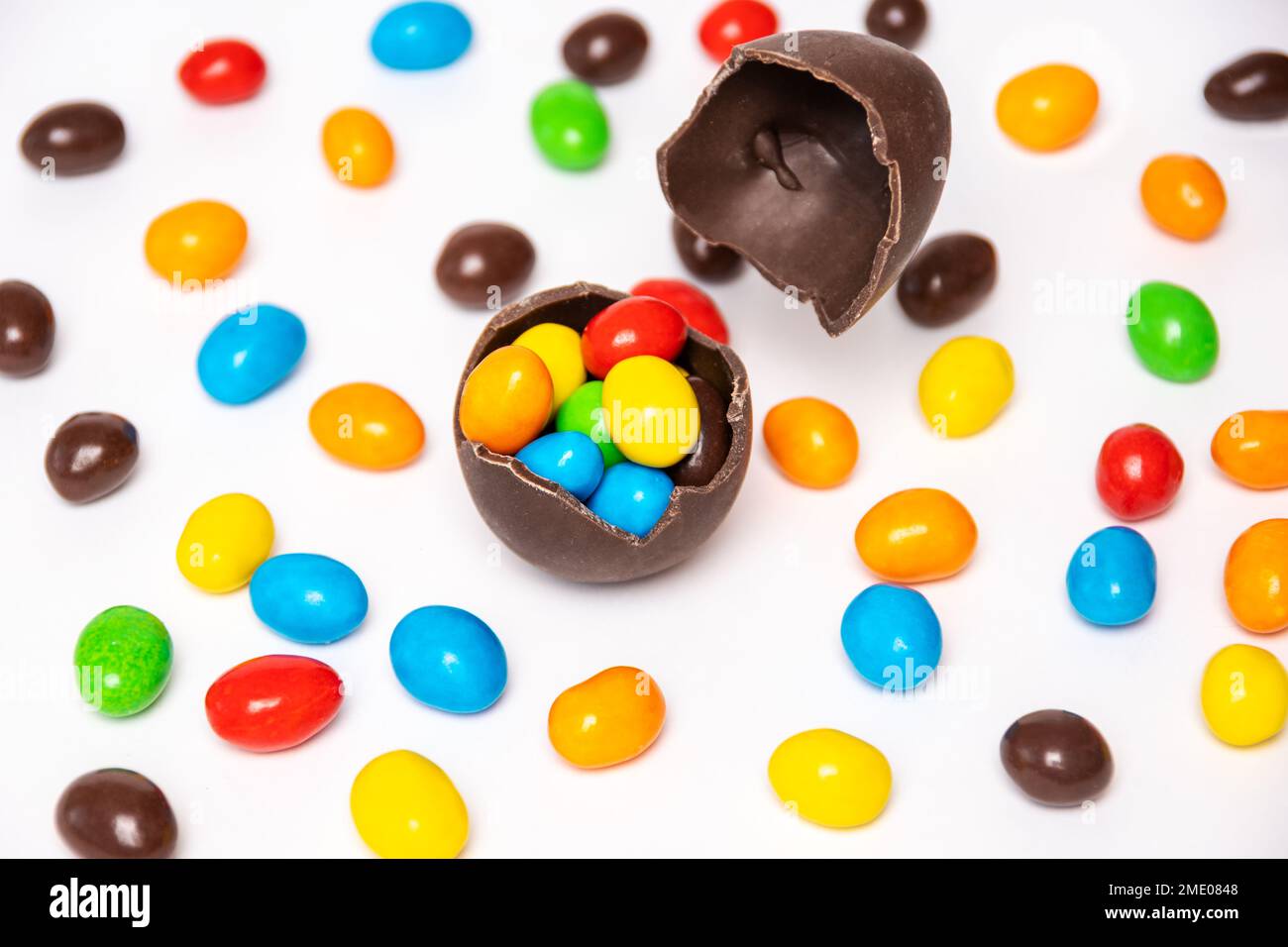 Broken chocolate easter egg with colorful candy decorations on a white ...