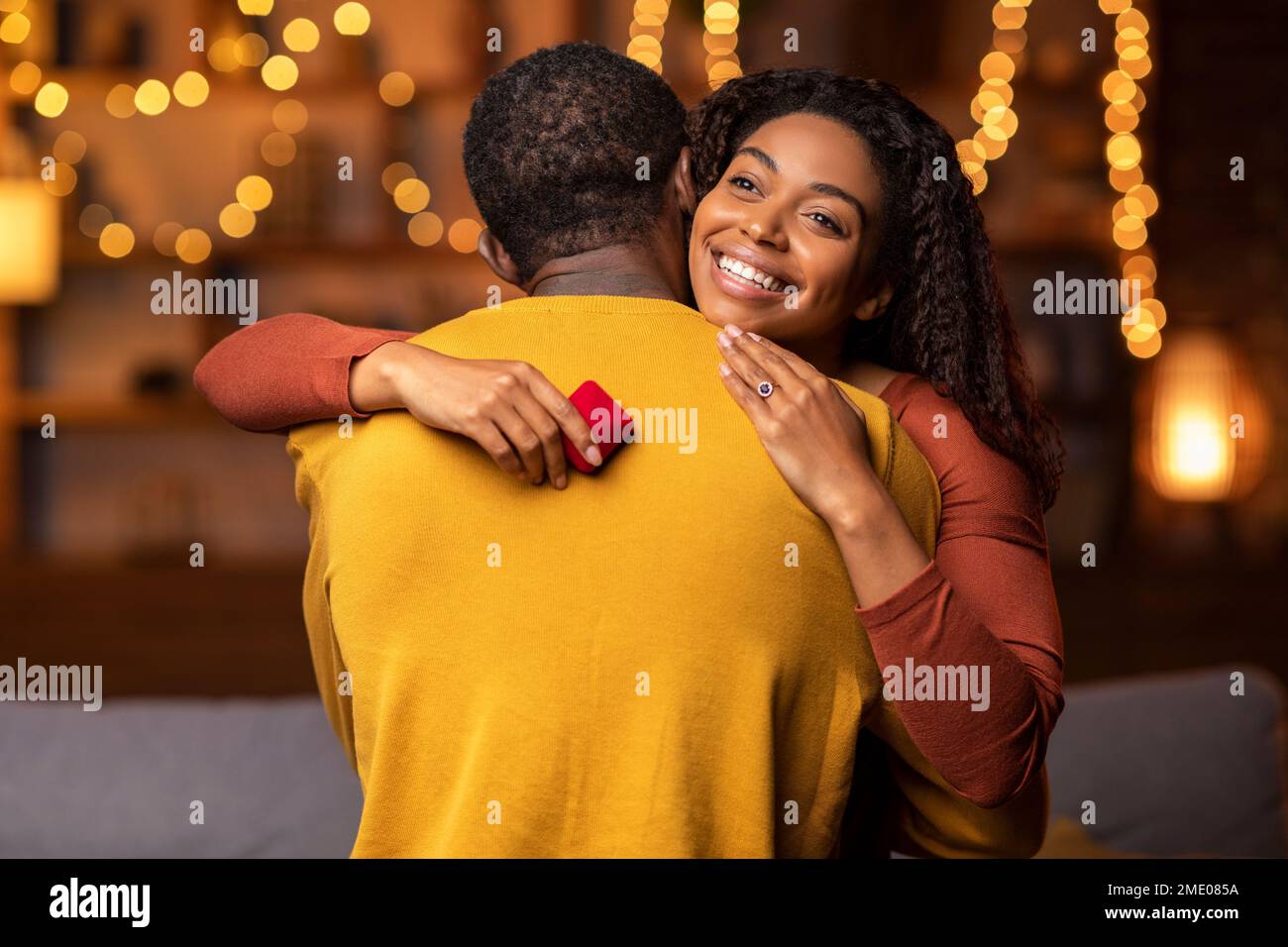 Happy african american woman with engagement ring hugging her fiance Stock Photo