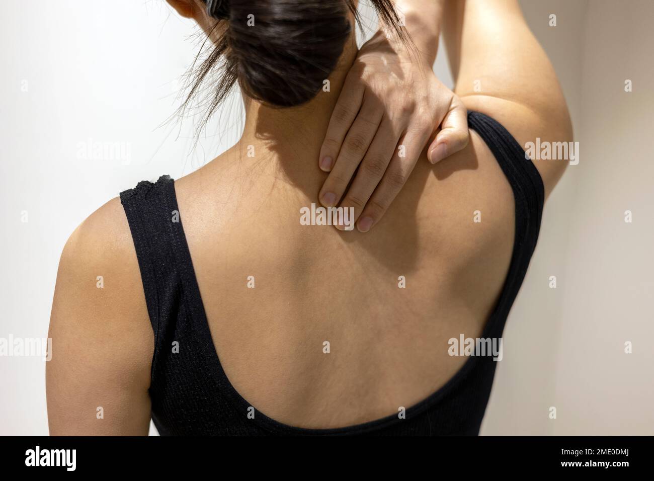 Woman puts her hand on neck and shoulder in black sportswear Stock Photo