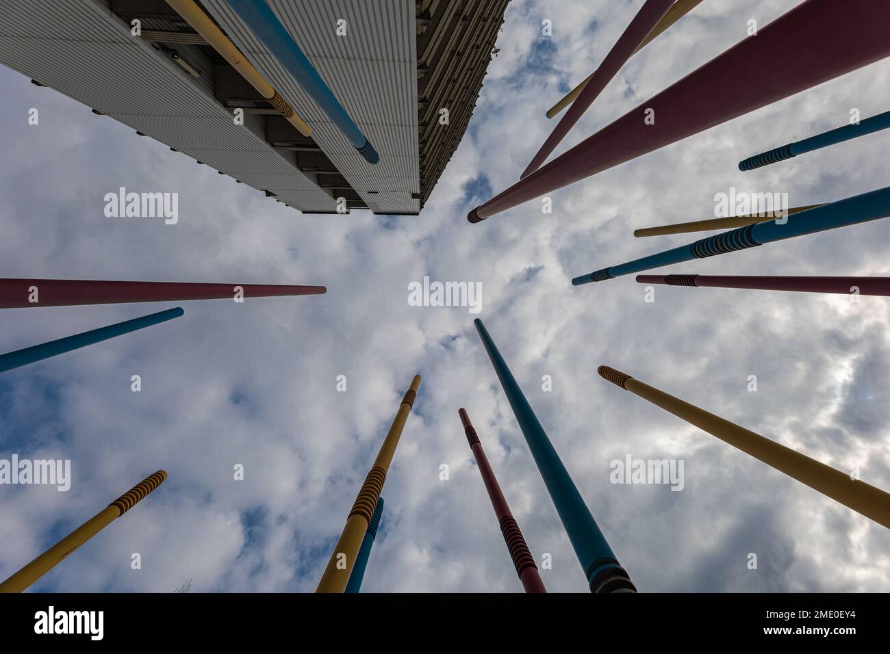 A lot of high colorful poles at kids playground next to modern estate