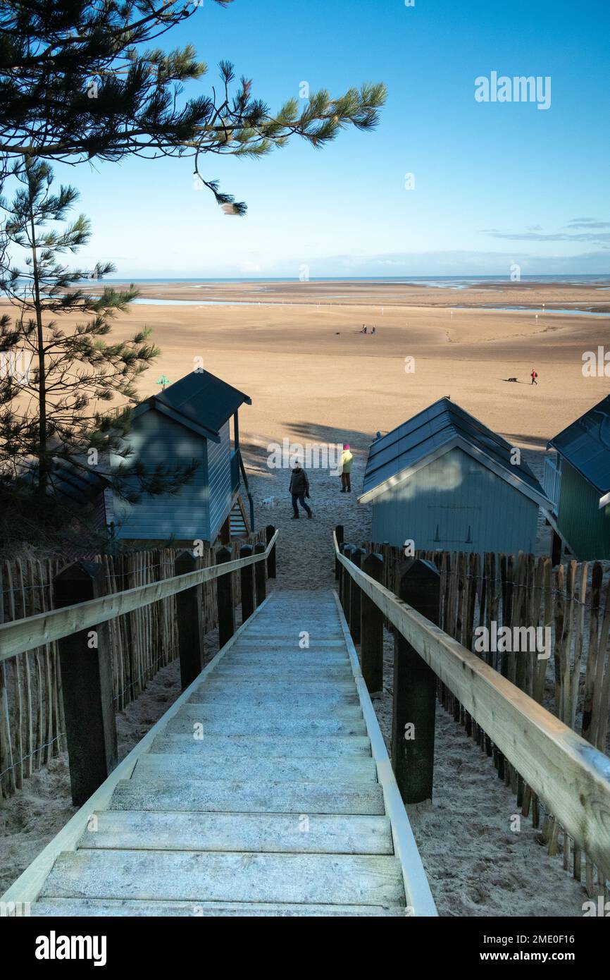 Steps between beach huts leading to beach with view accross the sand to sea at Wells on Sea North Norfolk East Anglia England Stock Photo