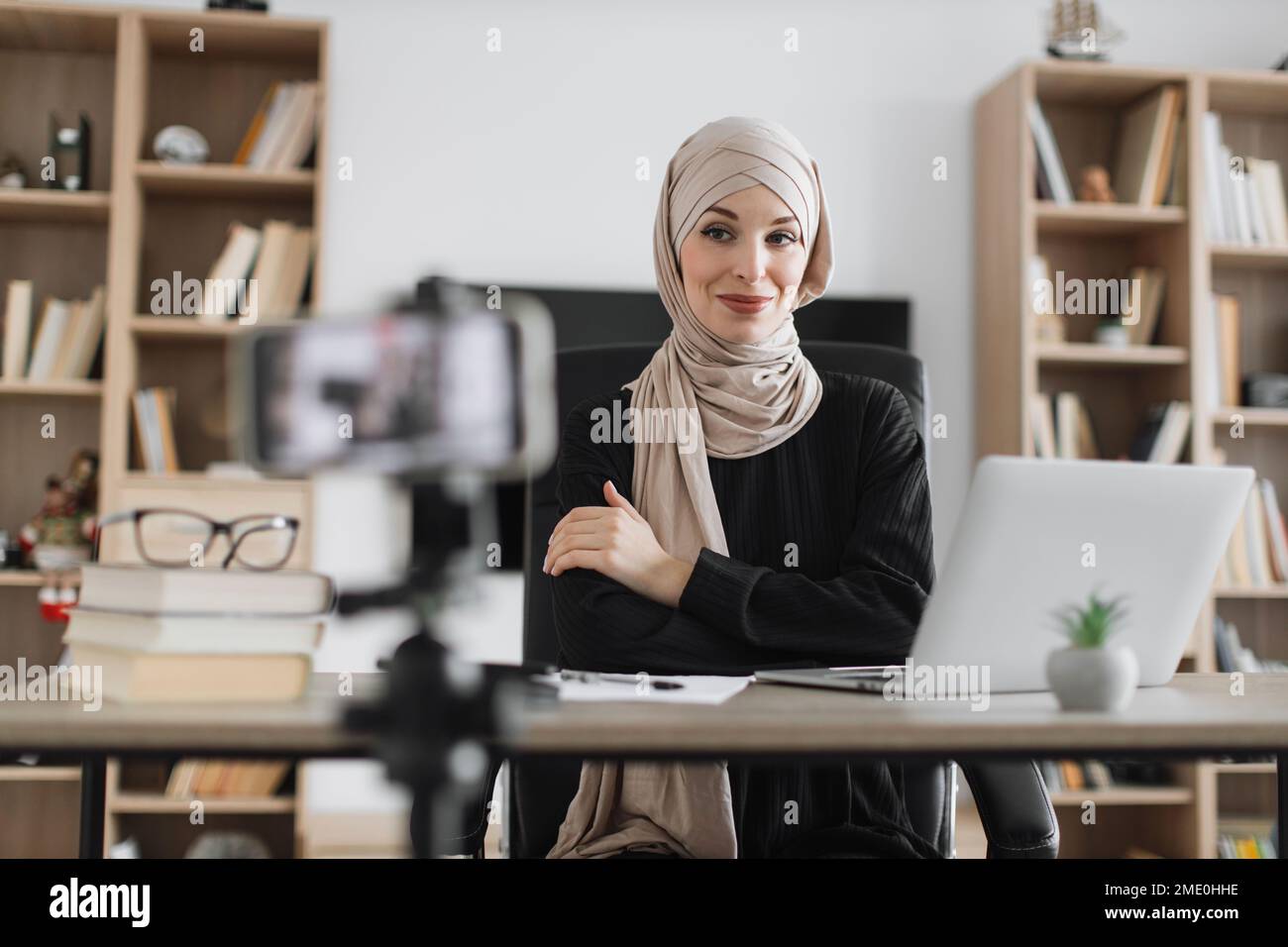 Beautiful muslim woman in hijab talking while looking at and recording ...