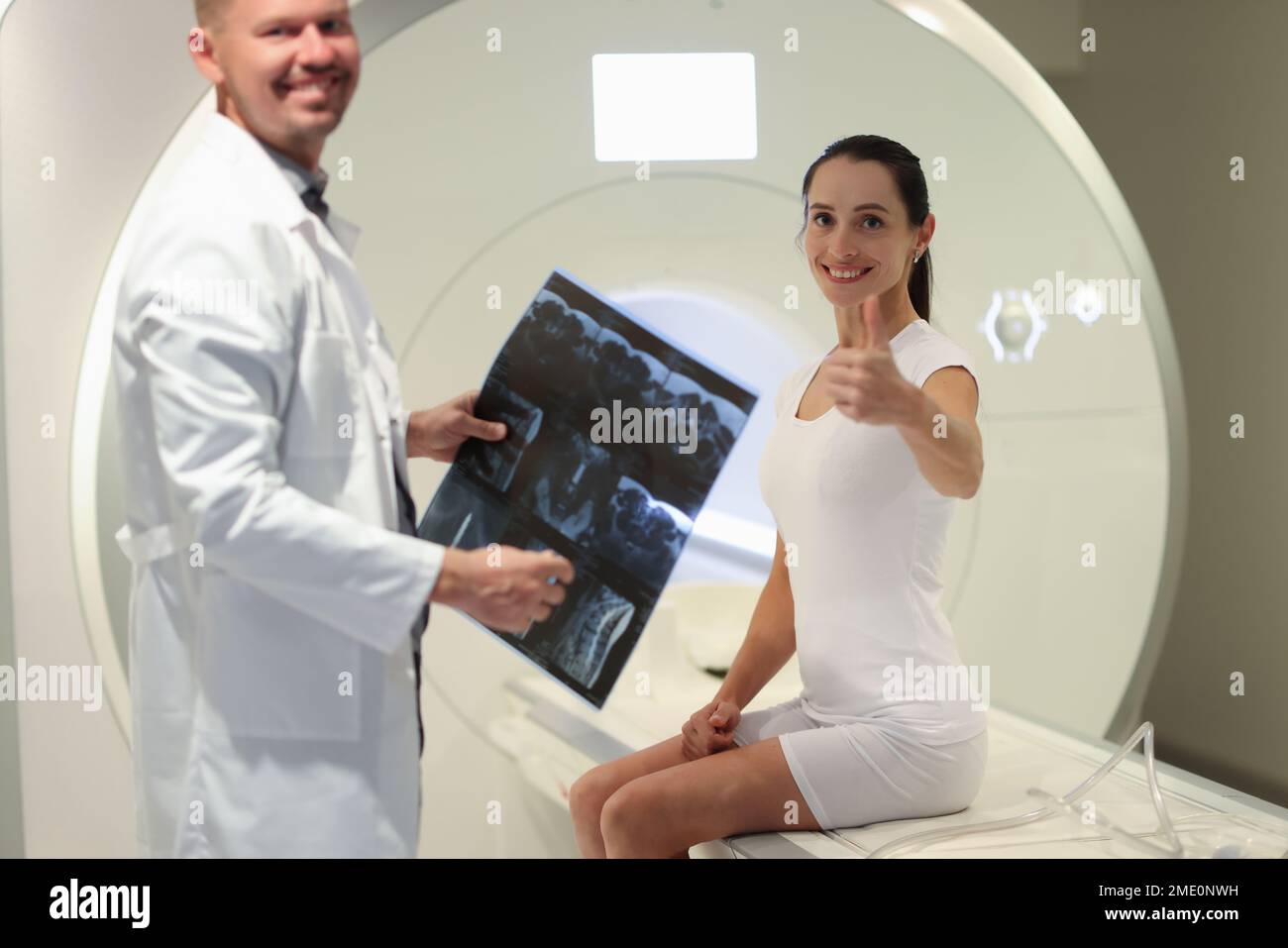 Radiologist holds MRI scans results while standing near CT scanner and