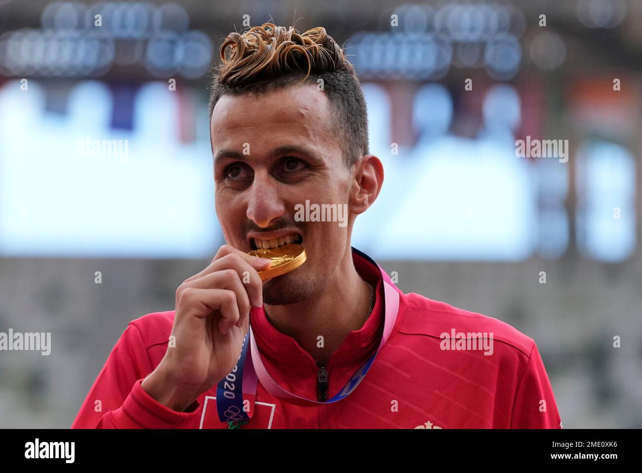 Soufiane El Bakkali, of Morocco, bites his gold medal on the podium for