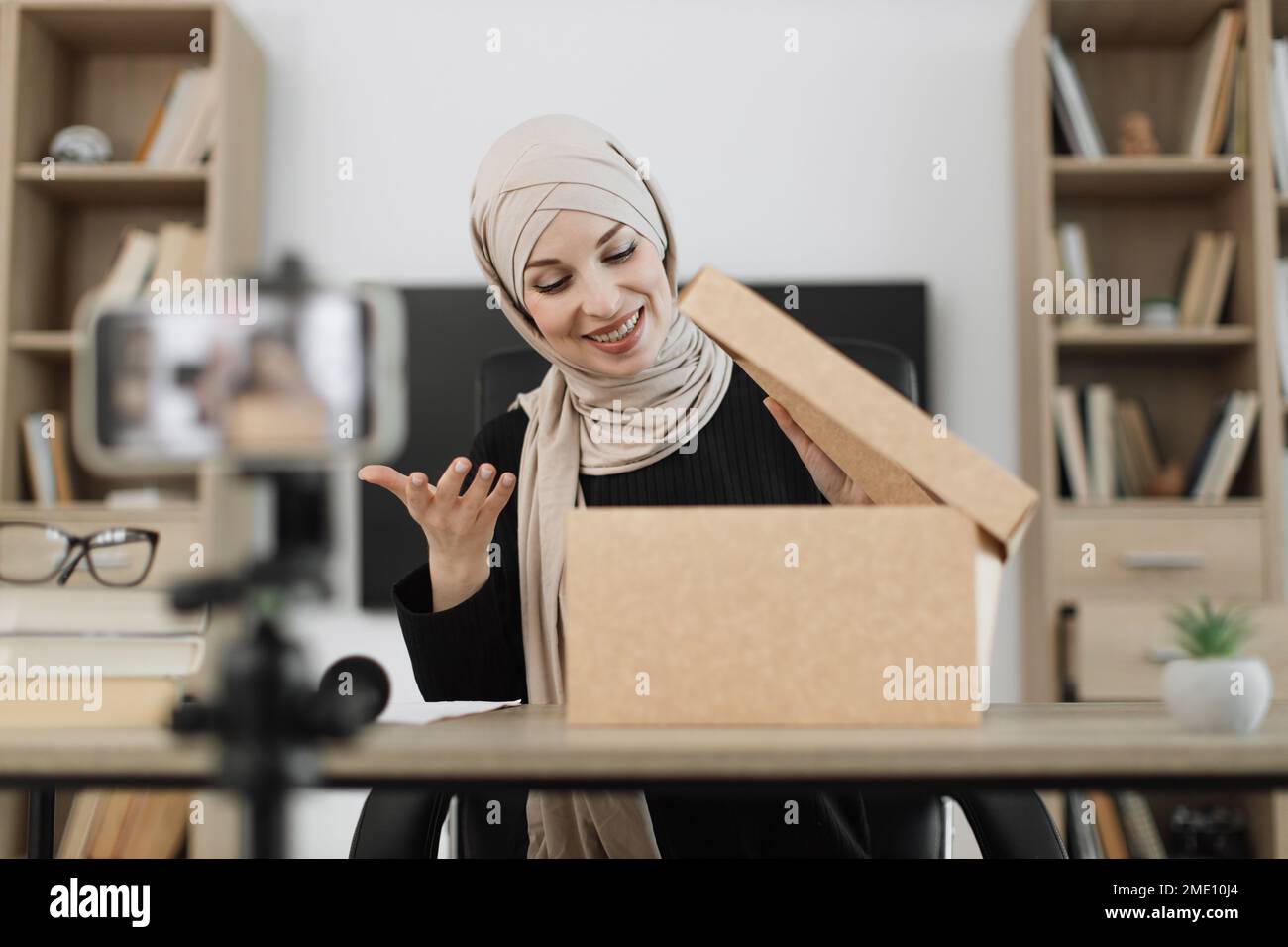 Excited smiling muslim woman in casual wear and hijab recording video ...