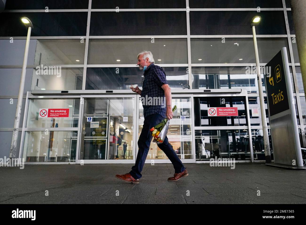 A man holds a bouquet of flowers at Gatwick Airport, in London, Monday, Aug. 2, 2021. Travelers