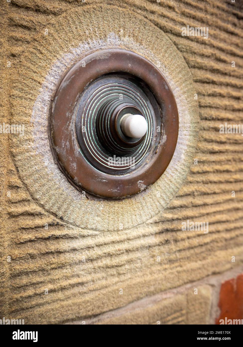 Historical style door furniture, wall mounted and framed circular style bronzed doorbell. Stock Photo