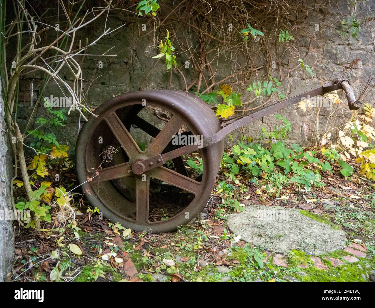 In the grounds of Ruthin Castle, Ruthin, North Wales, lies the old grass roller, long ago abandoned to be a decoration instead of a tool. Stock Photo