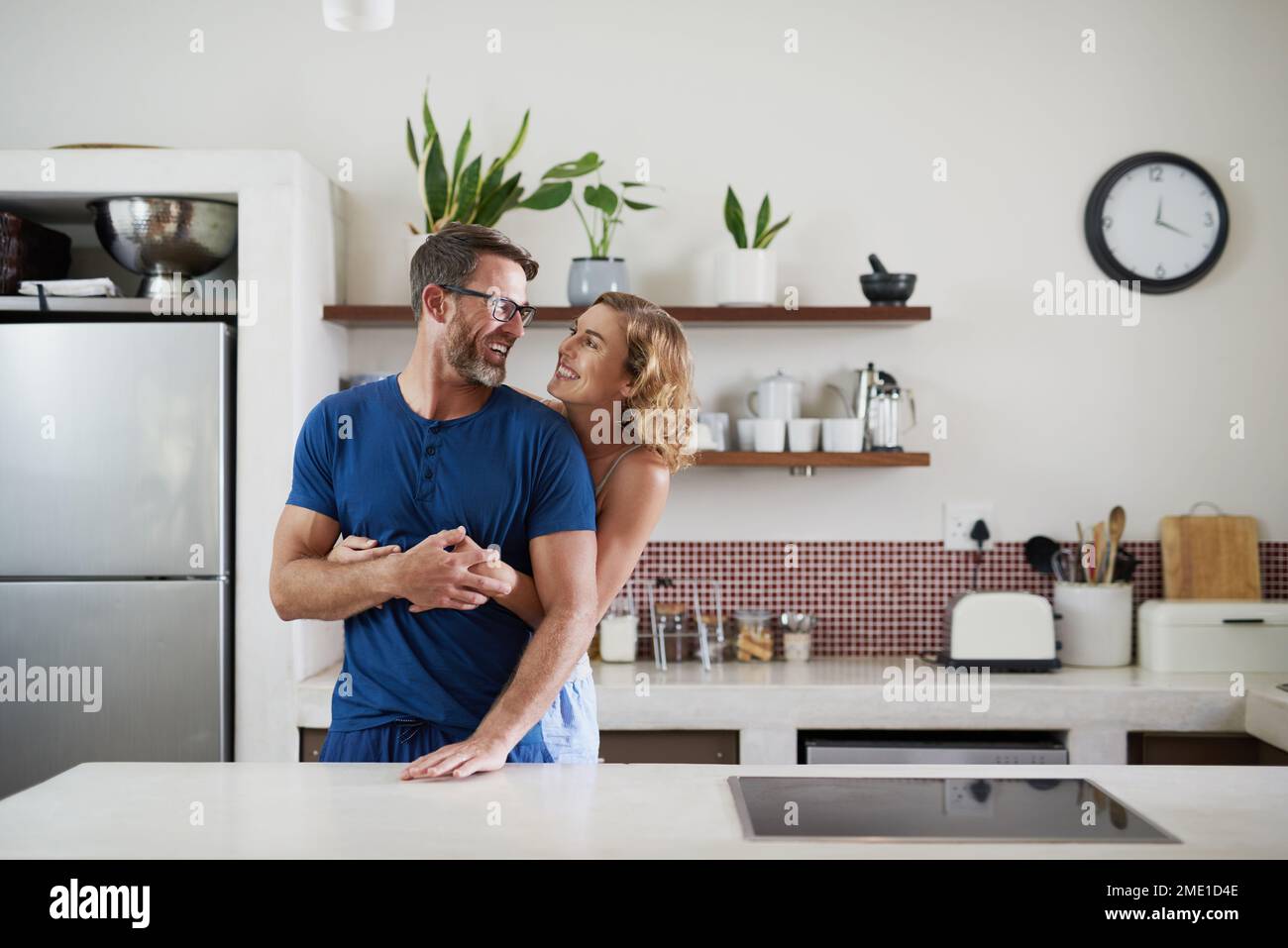 How bout some breakfast my love. a happy middle aged couple embracing in the kitchen at home. Stock Photo