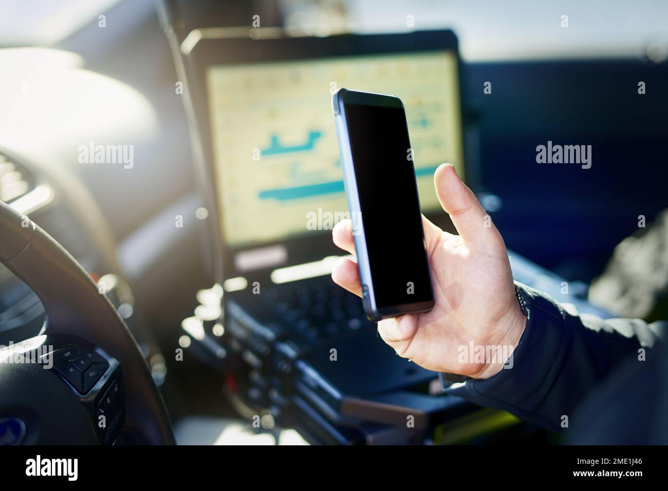 Wireless technology is keeping him up to date. an unrecognizable male police officer using his cellphone while out on patrol. Stock Photo