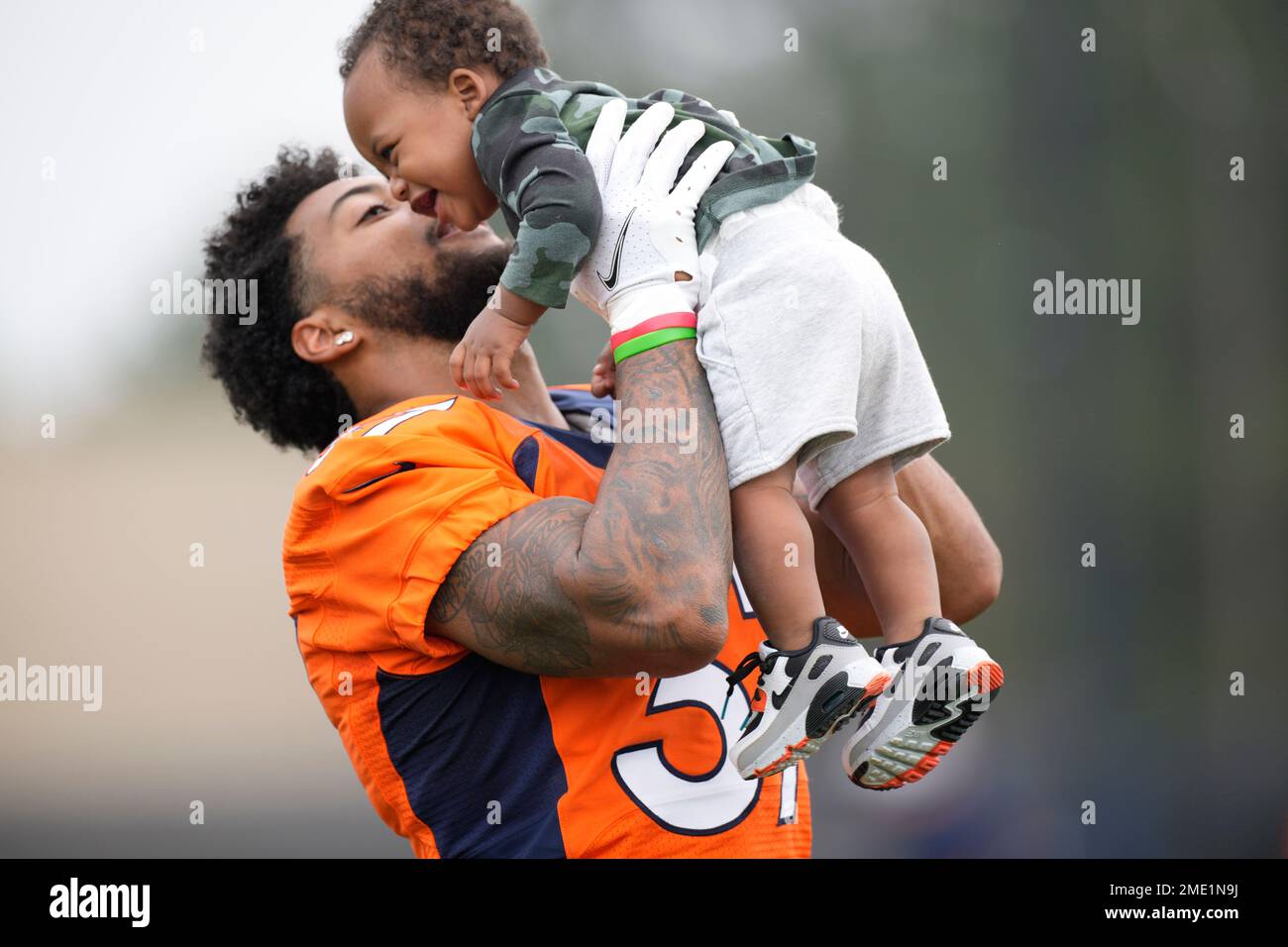 Nine-month-old James Locke IV, right, is held by his father, Denver Broncos  defensive back P.J. Locke (37) after taking part in drills at an NFL  football training camp at team headquarters Saturday