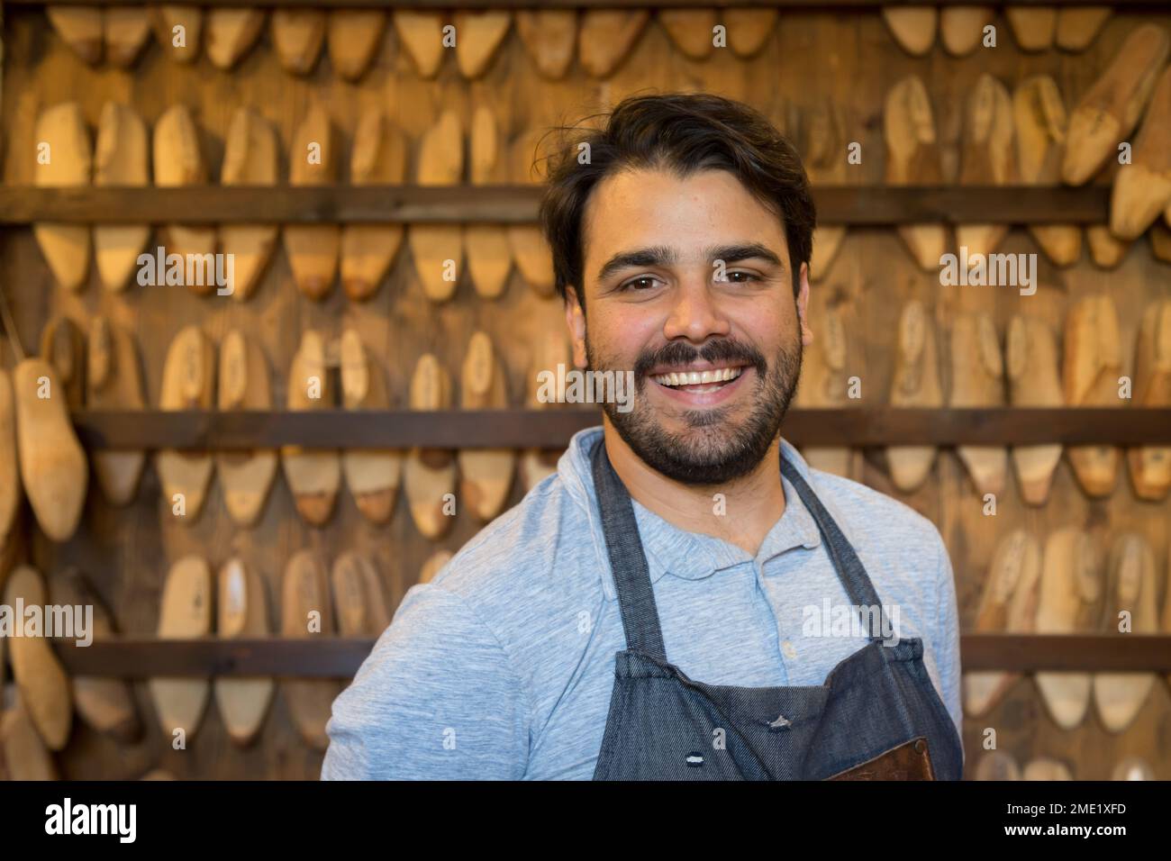 Shoemaker standing in front of a wall of lasts used for handmade leather Italian shoes, at Roberto Ugolini workshop in Florence, Tuscany, Italy. Stock Photo