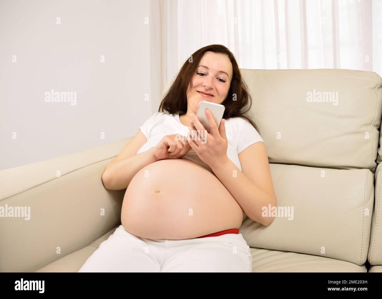 Pregnant woman texting with a smart phone Stock Photo
