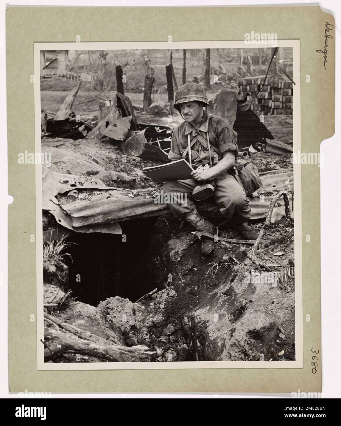 Coast Guard Combat Artist Paints in the Battle Fields. Coast Guard Combat Artist Ralph Deburgos, Seaman First Class, of Silver Spring, Maryland, makes sketches on a shell-torn area of Leyte Island in the Central Philippines. He is shown here at the mouth of a Jap machinegun nest. Serving on a Coast Guard-manned LST, Deburgos participated in the initial landing operations on Leyte on A-Day under enemy artillery and sniper fire. His commanding officer cited Deburgos for creditably manning his station while his ship was under 17 air attacks of Dulag and Tacloban villages during which two planes w Stock Photo