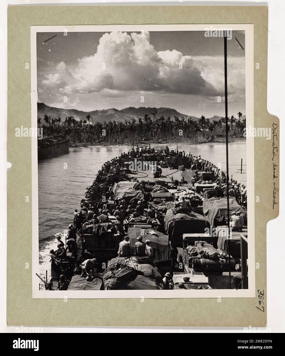 Destination Dead Ahead. A Coast Guard-manned LST, loaded to the Gunwales with trucks, tanks, guns and Yankee fighting men, pokes its blunt snout toward the palm-lined beach of Leyte Island in the Philippines. The Thunderous bombardment of U.S. fleet guns has quieted. The first waves of invaders have struck and now the ponderous LSTs, backbone of amphibious assault, slides toward the unloading point in the battle center of the central Philippines. Stock Photo