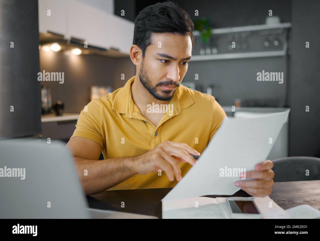 Businessman, home office and documents by laptop in kitchen for focus, small business growth and opportunity. Digital entrepreneur, business owner and Stock Photo