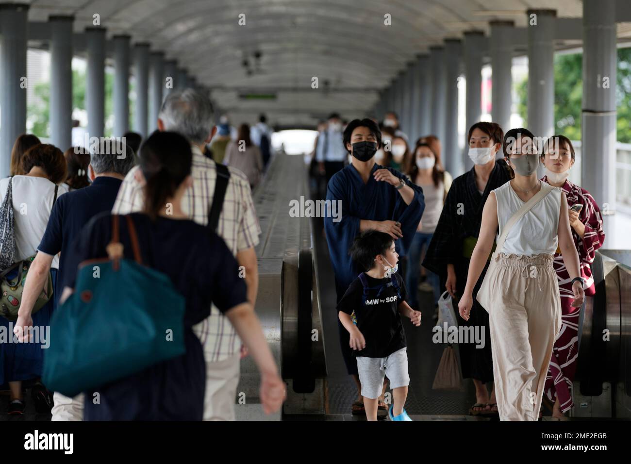 People wearing protective masks pass through a pedestrian bridge friday