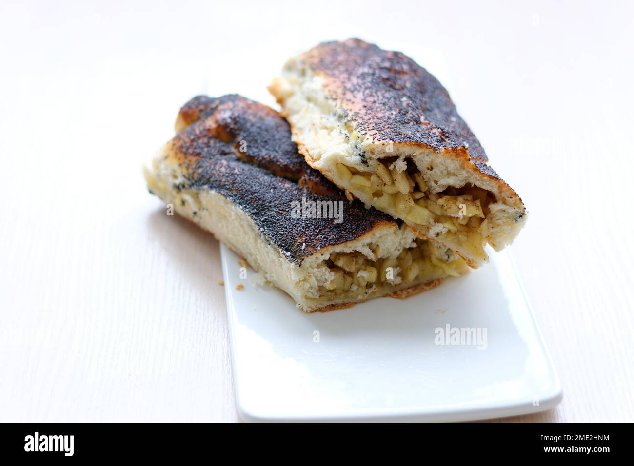 strudel with apples sprinkled with poppy seeds on white flat plate and ...