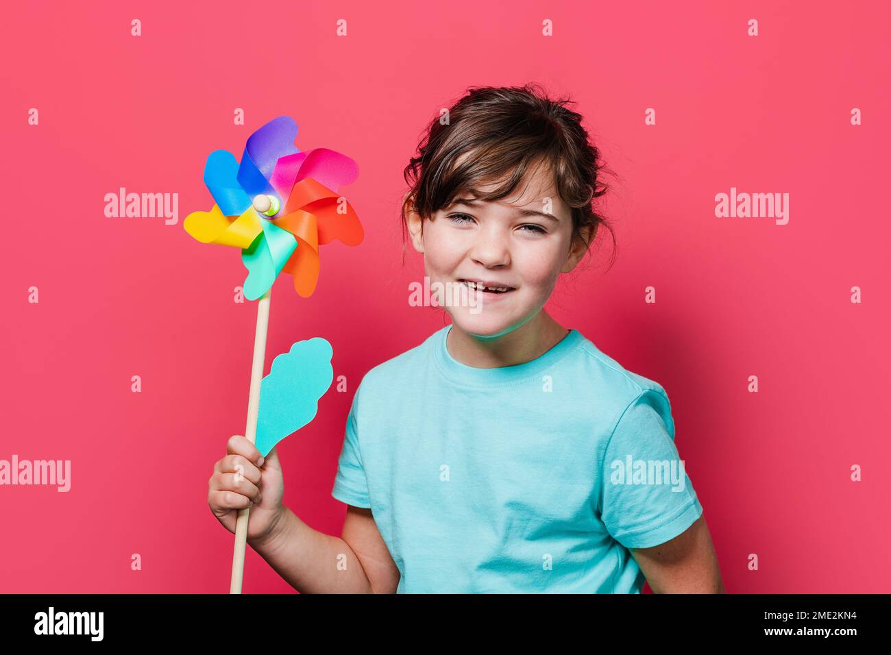 Adorable smiling child standing against pink background with colorful ...