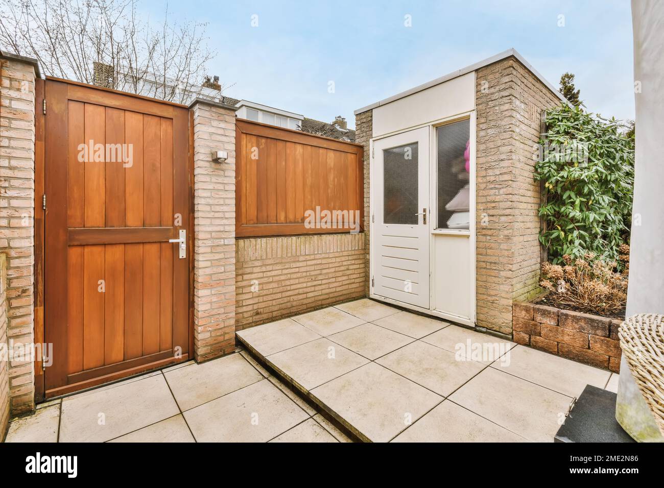 Modern wooden door of residential house in countryside with brick fence